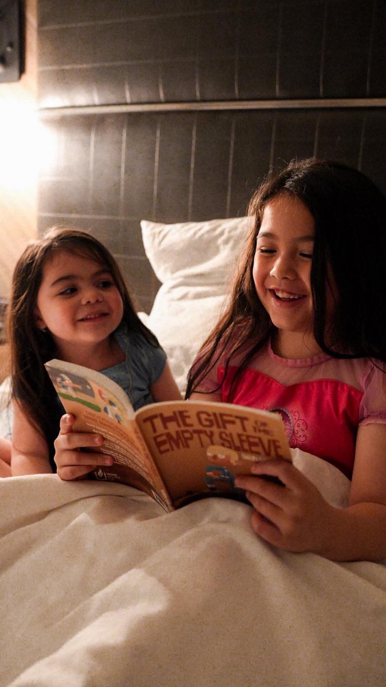 Two sisters laughing while reading The Gift of the Empty Sleeve