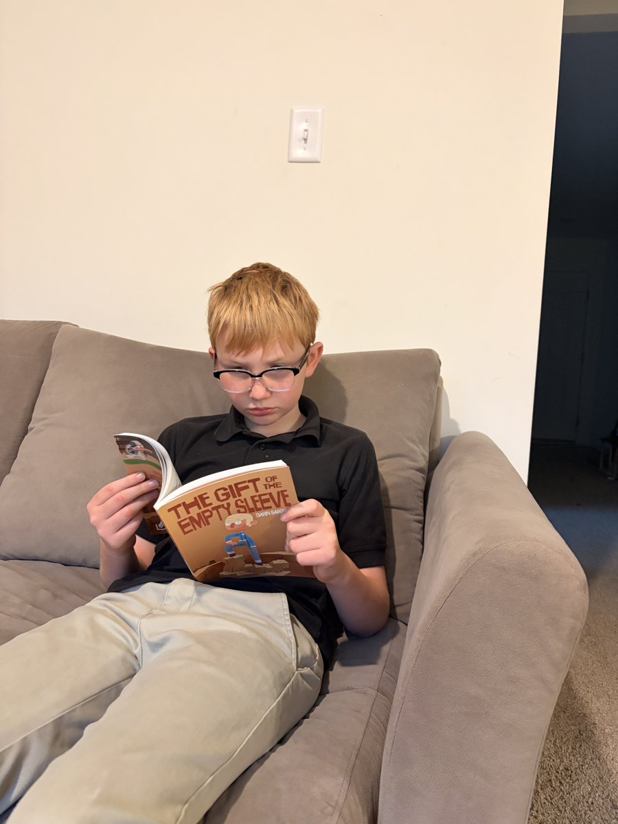 Boy reading The Gift of the Empty Sleeve on the couch