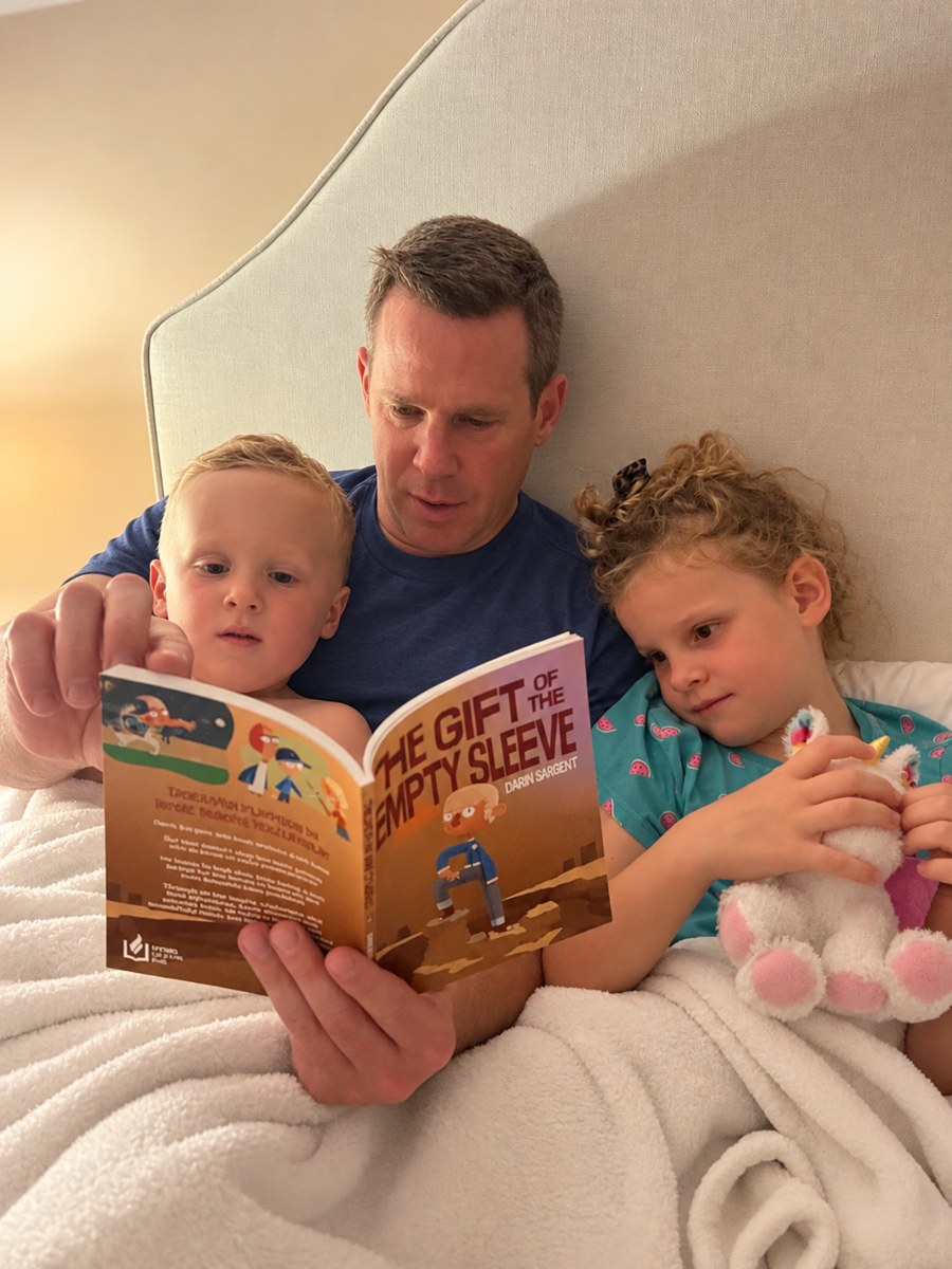 A dad reading The Gift of the Empty Sleeve to his two kids at bedtime