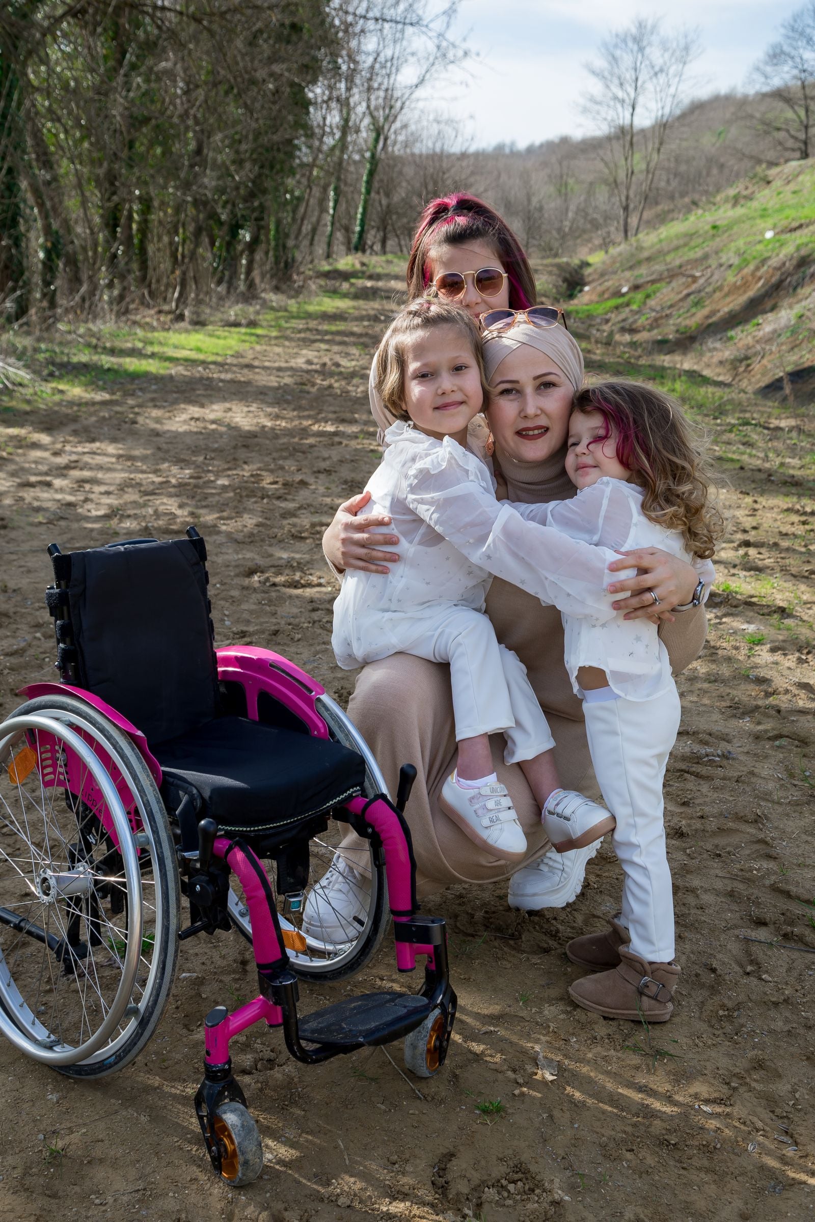 Mother hugging her daughters beside a wheelchair